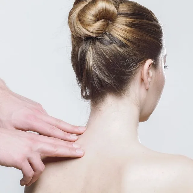 Hands treating a patient's neck and shoulder
