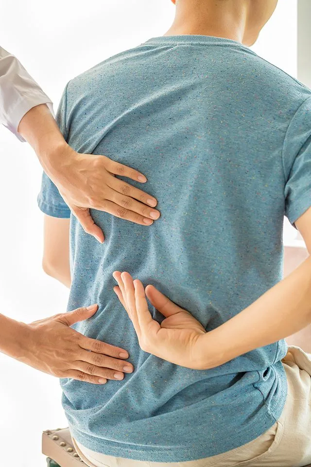 Chiropractor's hands examining a patient's back